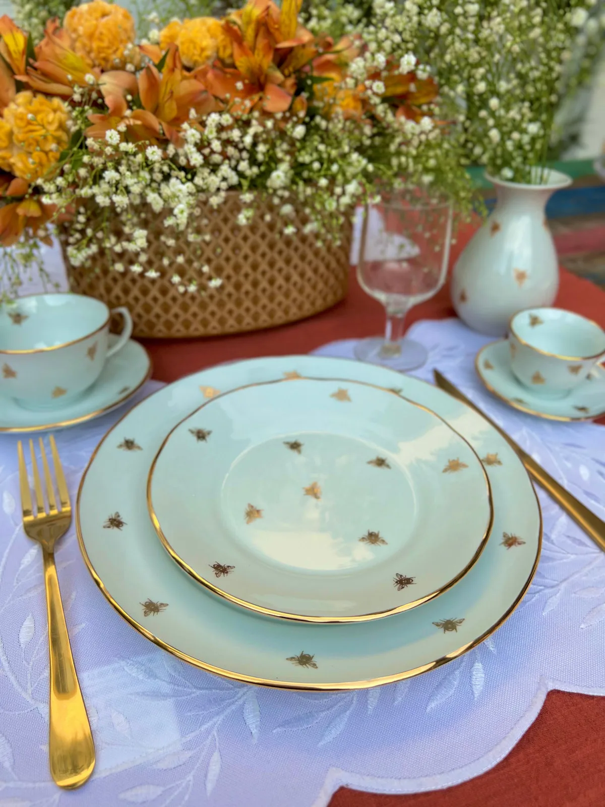 Mesa posta com pratos de porcelana pintados à mão com abelhas douradas