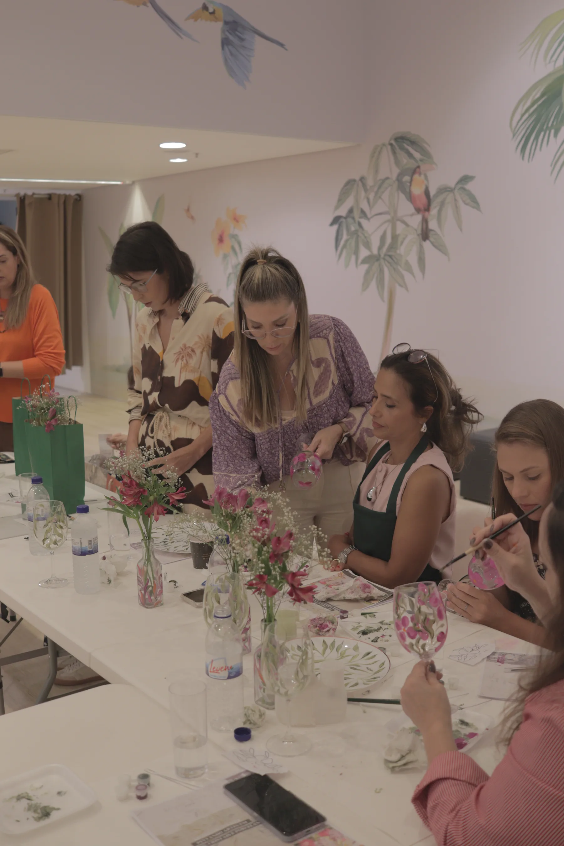 Convidadas pintando taças em um workshop corporativo
